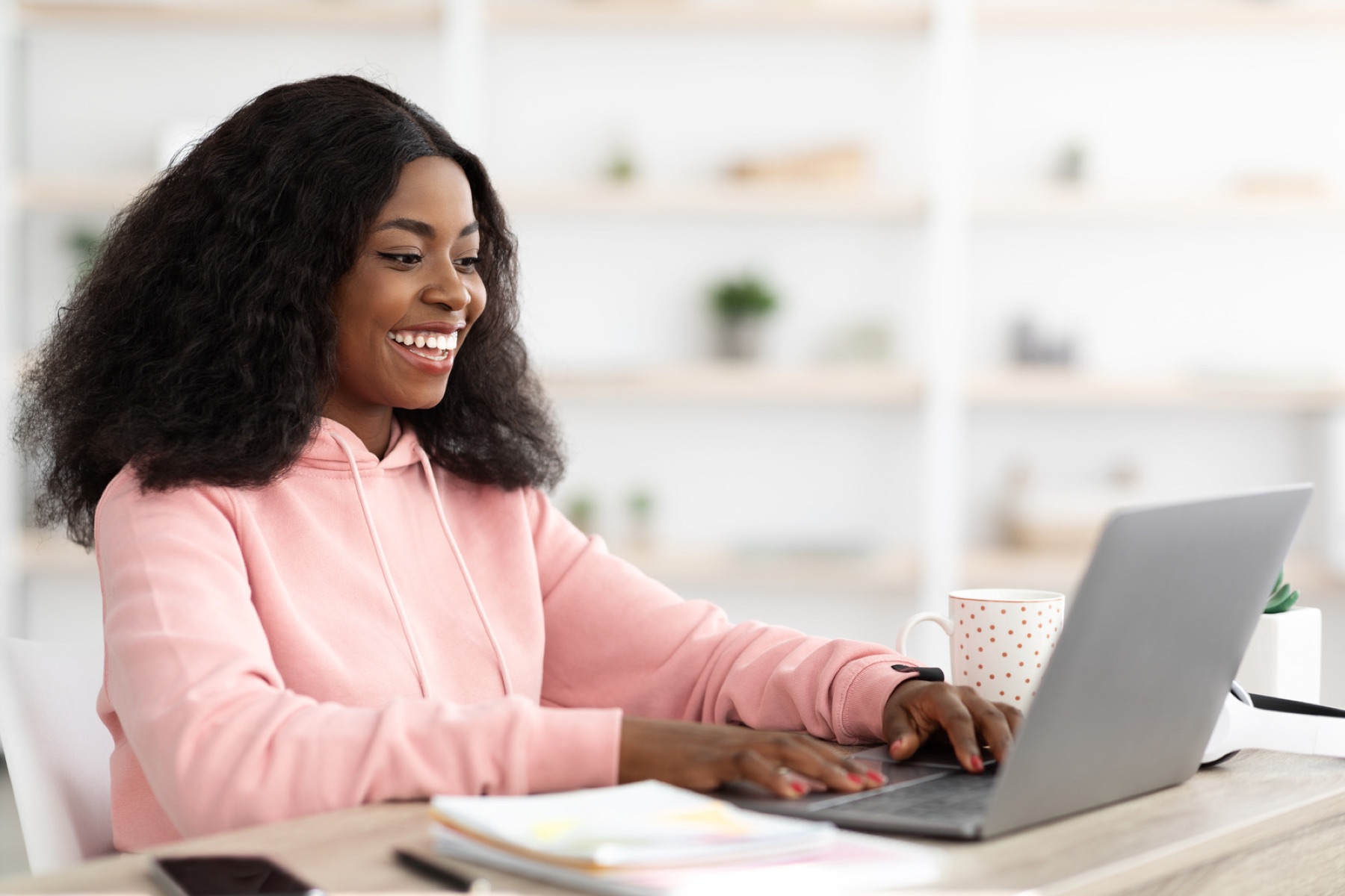 Une salariée souriante travaille sur son ordinateur dans un bureau lumineux